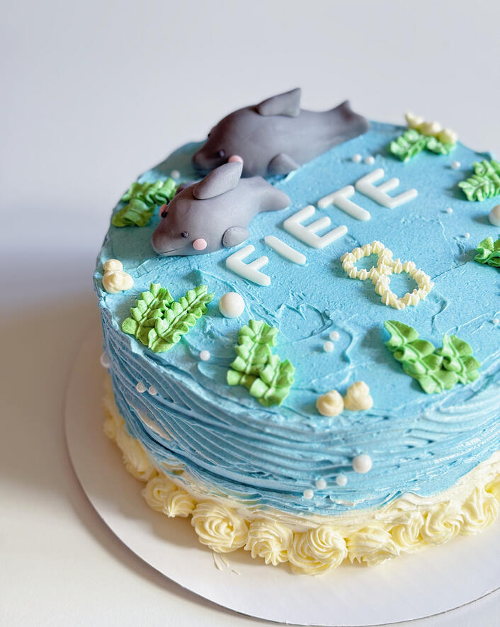 birthday cake with customer fondant topper dolphin and waves and seagrass decoration piping